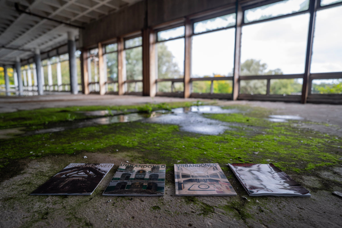 Urbandoned Issues 1–4 laid in a row on a moss-covered floor inside an empty building